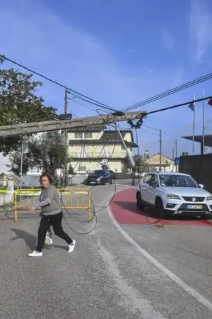 Um poste caído, ainda ligado com cabos no meio da rua.